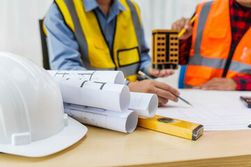 Two men, including a male Asian construction contractor engineer, discuss structural plans and...