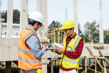 Two male construction workers, including an Asian engineer, meticulously review structural plans and design concrete columns and beams for a new residential build.