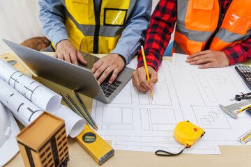 Two men, including a male Asian construction contractor engineer, discuss structural plans and...
