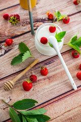 homemade sweet yogurt in a jar with strawberries, on a wooden table