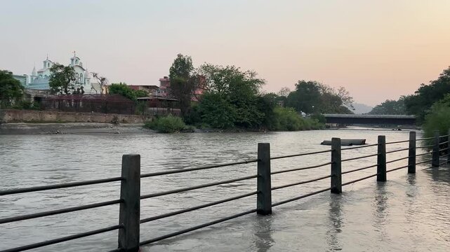 metal fence in water with trees and buildings in the background in Haridwar city, Uttarakhand, India