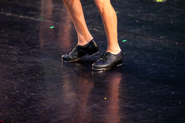 Tap dancing on stage - a close-up of tap shoes on a worn stage.