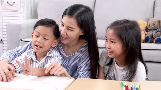 Multitasking mother teaching homework counting number reviewing basic math for cute sibling elementary school children, Asian mom woman take care kids enjoy playtime activity sitting on sofa together