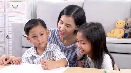 Cheerful Asian mother spend time with two sibling kids teaching homework drawing picture together in living room at home, free time children on holiday bonding happy relationship with mom parenthood