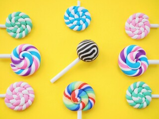 Colorful lollipops against a bright yellow background. Vibrant sweet candy pops
