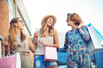 Shopping, group and women in city for discount, boutique sale and happiness by mall. Girl friends, laughing and walking with paper bags for memories, reunion and commerce together for bonding