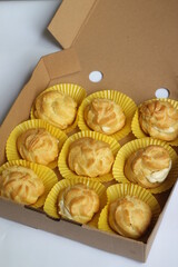 Nine kue sus, profiteroles, cream puffs or choux pastries in cardboard box. French dessert made of choux pastry, bake and filled with cream.