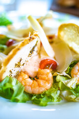 Caesar salad with shrimps and cherry tomatoes in restaurant.