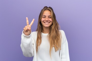 Smiling Woman in White Sweater Giving Peace Signs Against Purple Background