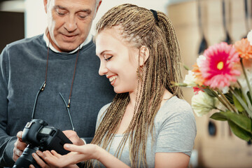 Senior man showing modern digital camera to young photographer w