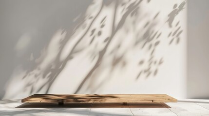 Empty copy space image of a wooden plank on a white wall background illuminated by sunlight casting a tree shadow Ideal for presenting products in a mockup scene
