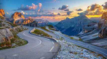 Summer sunset on the mountain road in Dolomites, Italy. The curved road meanders through rocks and stones, against a backdrop of blue sky with clouds. The empty highway passes through a mountain pass.