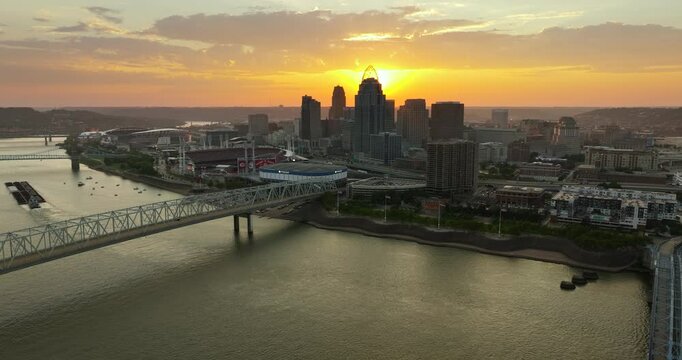Highway traffic on bridge in Cincinnati, Ohio with illuminated skyscraper buildings in downtown district. American city with business financial district at sunset