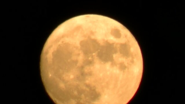 Dark night sky and orange, yellow, pink and silver rising full moon in December called Cold Moon - real time. Topics: season, cosmos, evening, dusk, atmosphere, space