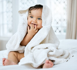 Baby, smile and towel on bed for hygiene with bath time, child skincare and wellness for growth in...