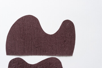 two textured brown paper shapes with wavy edges on blank paper