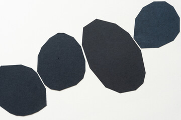 four black paper polygonal shapes on blank paper