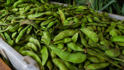 Fresh edamame displayed at a bustling farmers market. Vibrant green pods, harvested locally, ready for cooking. Healthy, nutritious snack or meal ingredient. Essence of farm-to-table produce