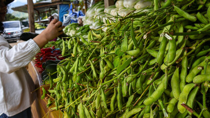 Fresh edamame displayed at a bustling farmers market. Vibrant green pods, harvested locally, ready for cooking. Healthy, nutritious snack or meal ingredient. Essence of farm-to-table produce