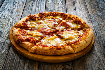 Pizza Serrano with cured ham, mozzarella cheese and mushrooms on wooden table
