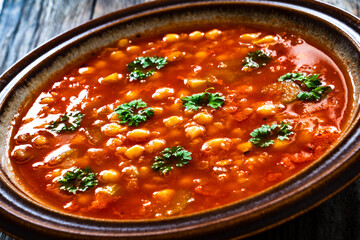 Moroccan cuisine - harira fresh vegetable soup with chickpeas and lentil on wooden table
