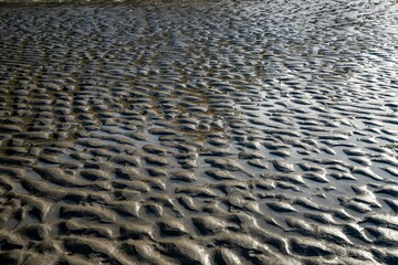 A pattern image of flat light on ripples in sand on a beach