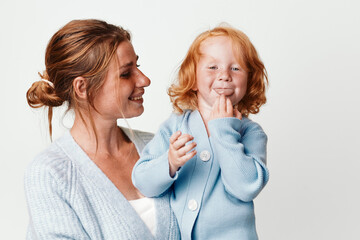 Mother and child smiling in front of white background, family love and happiness, parenthood and joyful moments