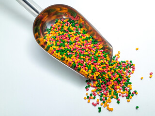 Colorful masterbatch granules mixed in a scoop, isolated on white background.Color pigment carrier...