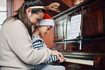 Mother, boy and piano at Christmas in home with smile, love or learning for music, performance or notes. Mom, child or son by keyboard for teaching, guide and helping for talent development at xmas