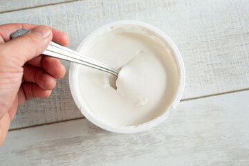 A top down view of a hand dipping a spoon into a package of dairy-free sour cream.