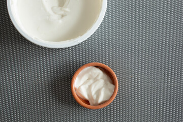 A top down view of dairy-free sour cream in its package and in a clay condiment cup.