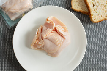A top down view of a plate of processed turkey deli meat slices.