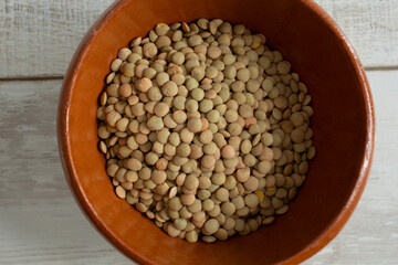 A top down view of a bowl of raw green lentils.