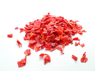 shredded red plastic waste ready for recycling, isolated on white background