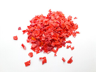 shredded red plastic waste ready for recycling, isolated on white background