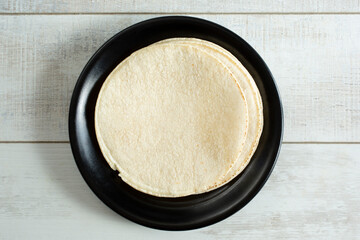 A top down view of a stack of corn tortillas on a plate.