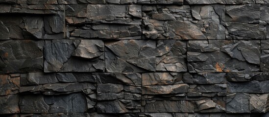 Stone wall made of dark-colored stones or slate. Background with a grungy appearance.