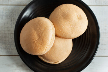 A top down view of gluten-free buns on a black plate.
