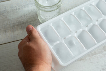 A view of a hand prepping an ice cube tray.