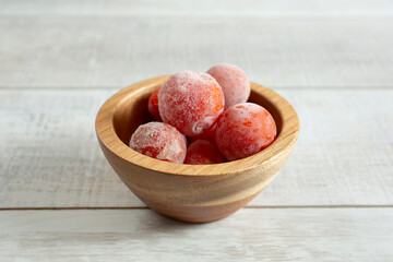 A view of a pile of cherry tomatoes in a small wood bowl.