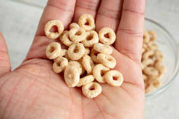 A top down view of a pile of toasted o's cereal in the palm of the hand.