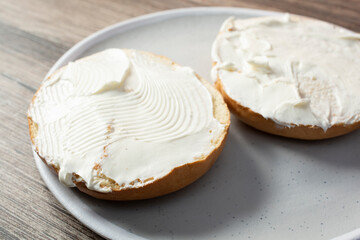 A view of a sliced bagel, with cream cheese spread, on a plate.
