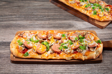 A view of a flatbread, featuring toppings as bell pepper, sausage and cheese.
