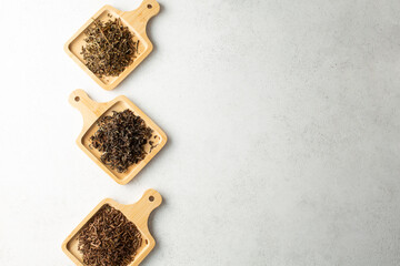 A top down view of assorted loose leaf tea on bamboo saucers, on the left side of the frame.