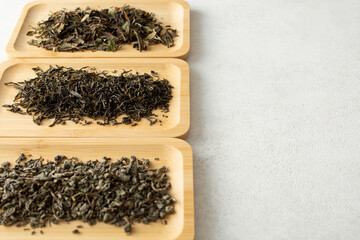 A view of assorted loose leaf tea on bamboo trays, on the left side of the frame.