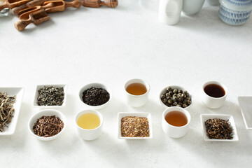 A view of a row of assorted loose leaf tea and tea liquor, on the bottom half of the frame.