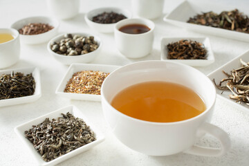 A view of a teacup, surrounded by assorted loose leaf tea and tea liquor.