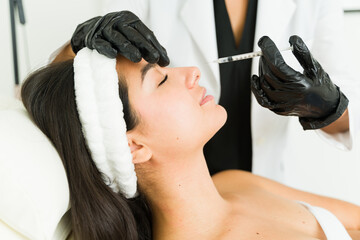 Naklejka premium Skilled doctor in a clinic setting provides a botulinum toxin treatment to enhance the beauty of a young female patient