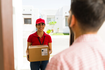 Delivery woman smiling and handing a package to a customer during a home delivery