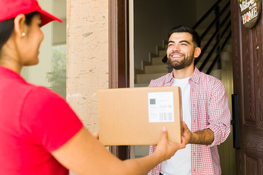 Handsome young man happily receiving a package from a female delivery person at his doorstep
